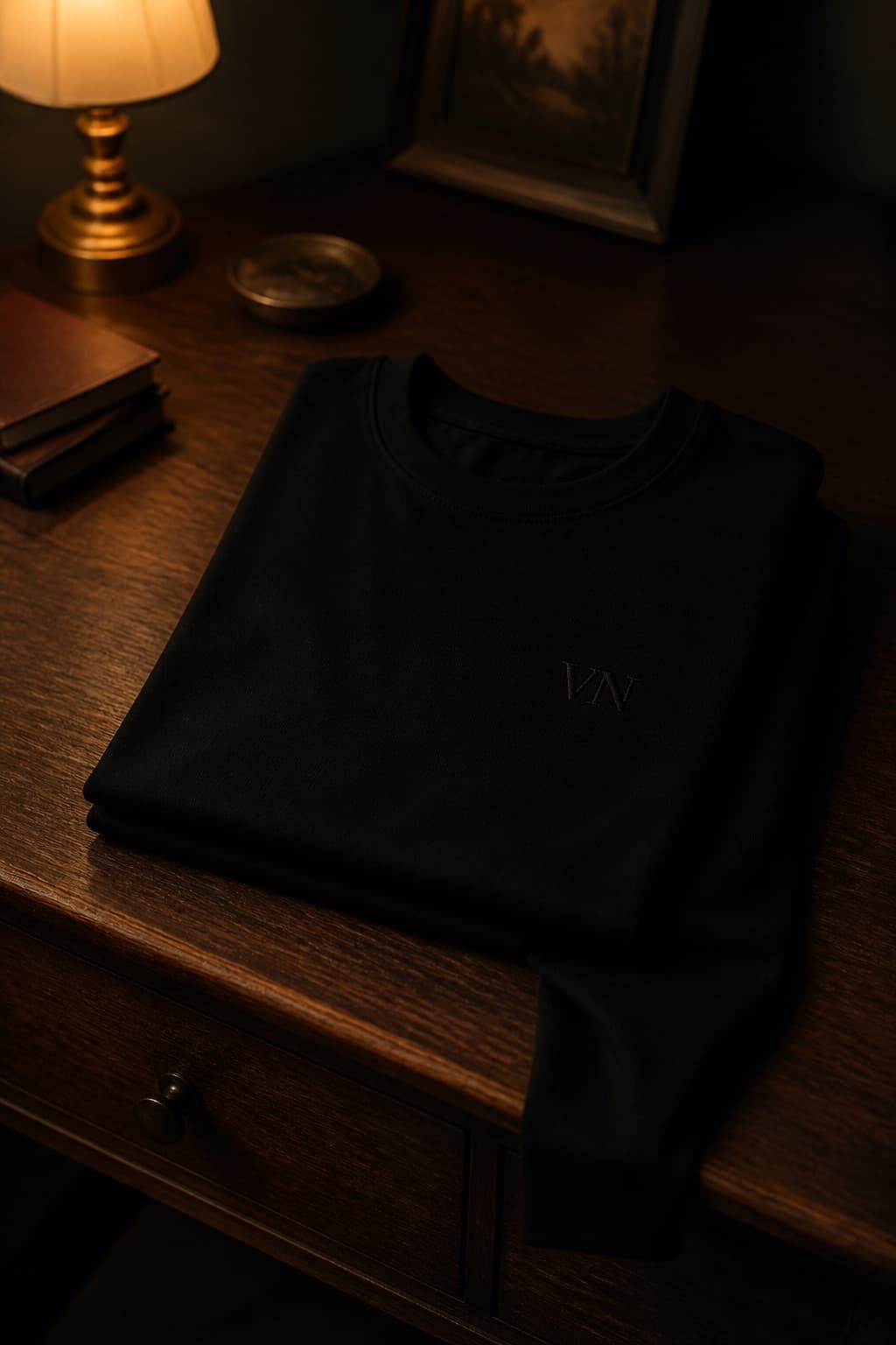 Black heavyweight crewneck t-shirt folded on dark walnut, one sleeve falling